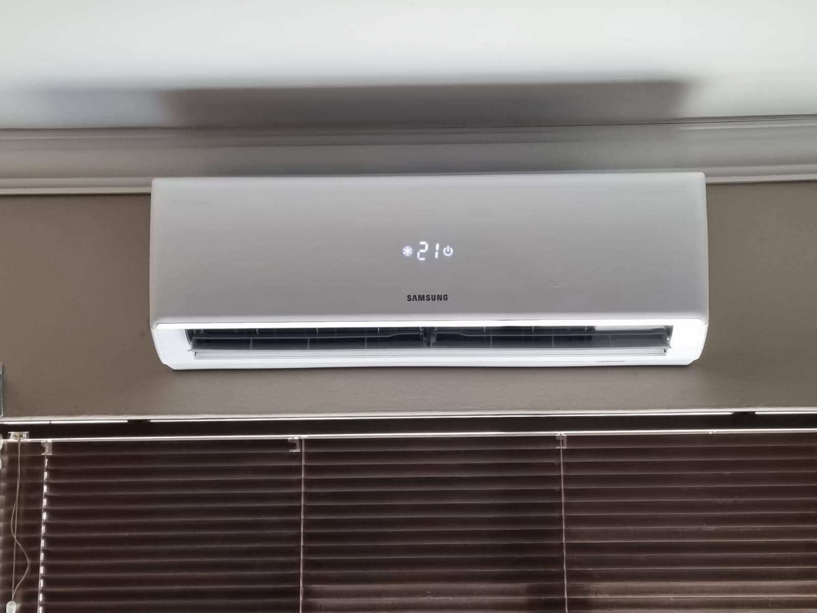 Close-up of Samsung split-unit air conditioner control display set to 21 degrees