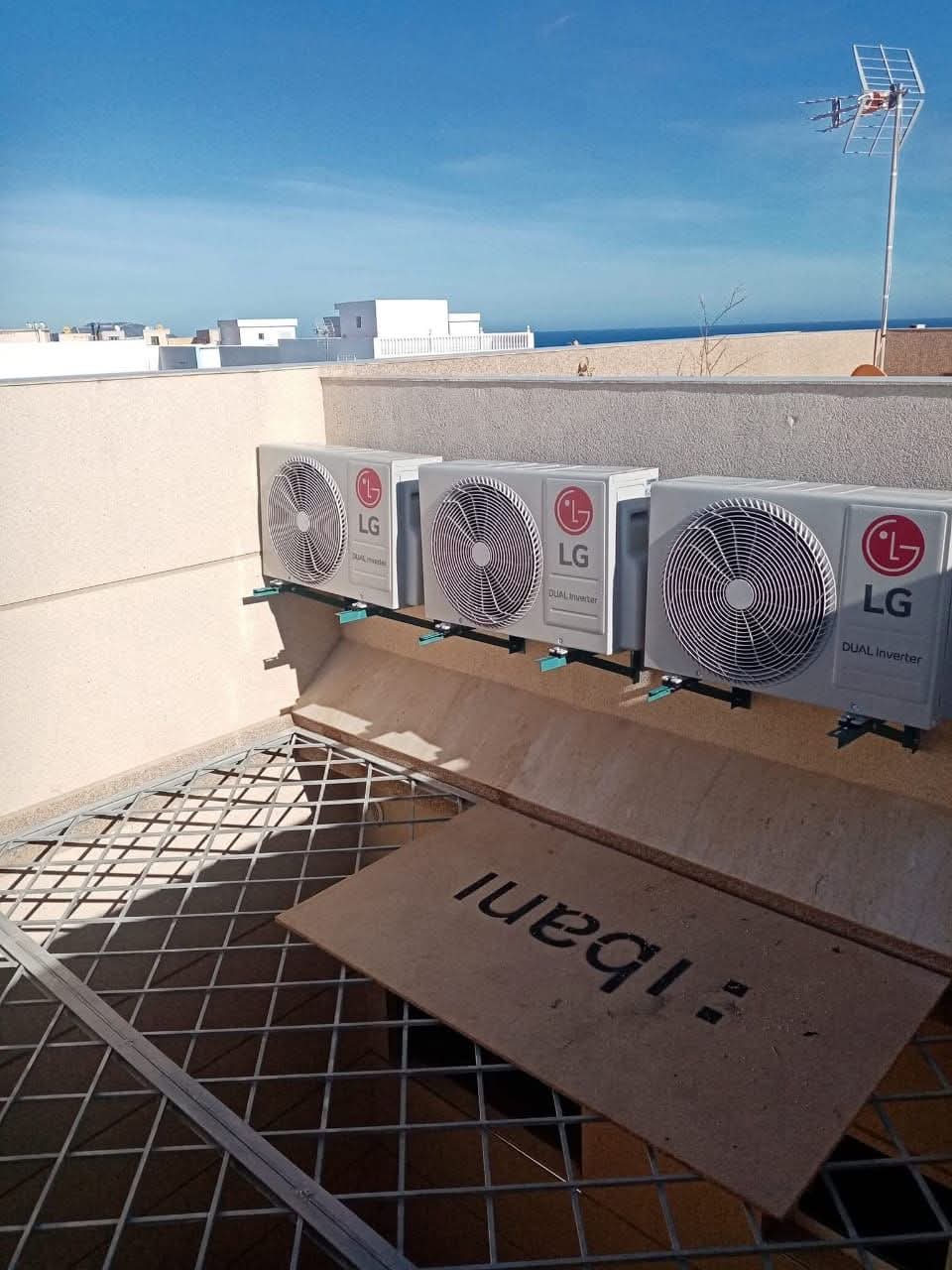 Three LG dual inverter outdoor air conditioning units mounted on a rooftop wall with sea view